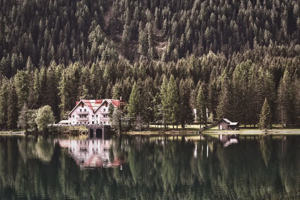 Tranquil lakeside scene with a cozy cabin surrounded by lush forest reflections.